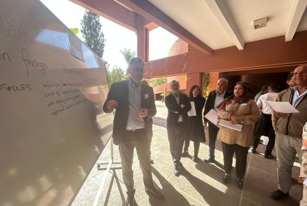 The picture shows people around a whiteboard discussing 